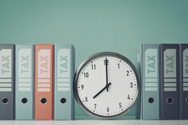 Ring binders that contain tax documents, financial statements, reports and clock, payment deadlines concept